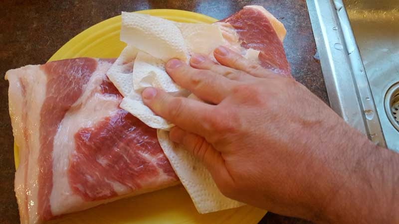 Patting a pork belly dry