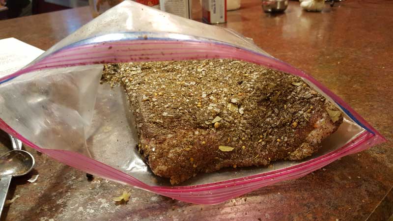 Pork belly covered in cure and spice in a ziploc bag