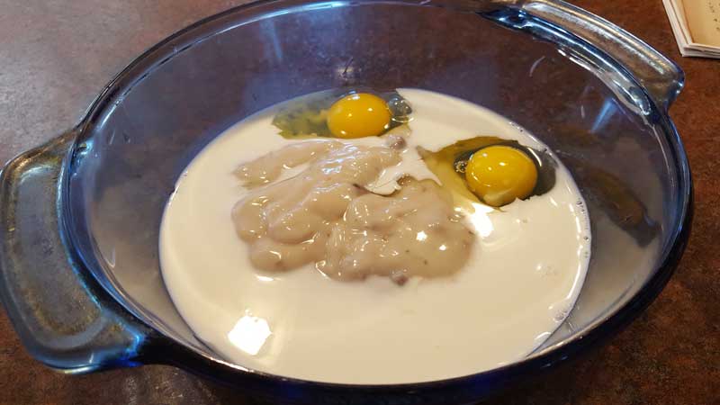 Eggs, mushroom soup and milk in a casserole dish.