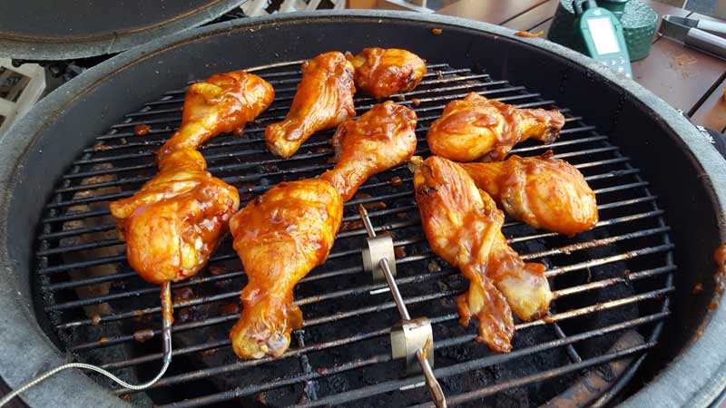 Chicken legs brushed with barbecue sauce on a Big Green Egg.