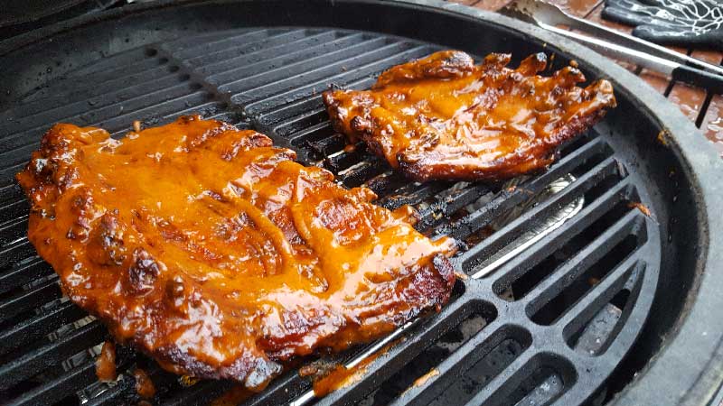 Baby back ribs meat side down and covered in cookie butter sauce on the Big Green Egg.
