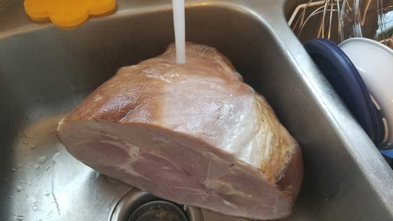 Ham in sink with water running over it.