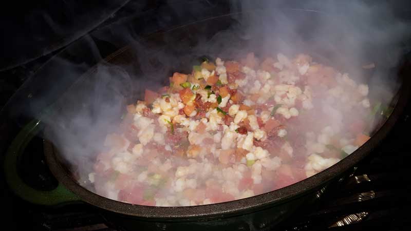 Tomatoes, shrimp, and chorizo cooking in a Dutch oven.