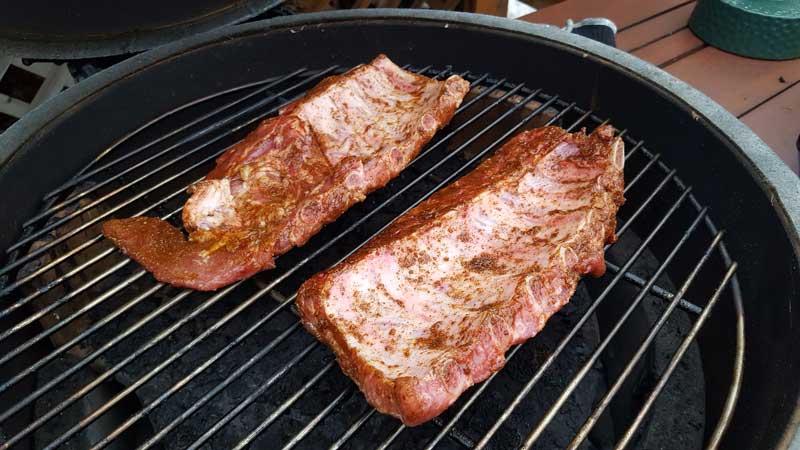 Baby back ribs meat side down on a Big Green Egg grate.