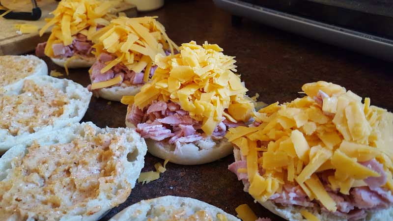Cheddar cheese on top of ham on an English Muffin.