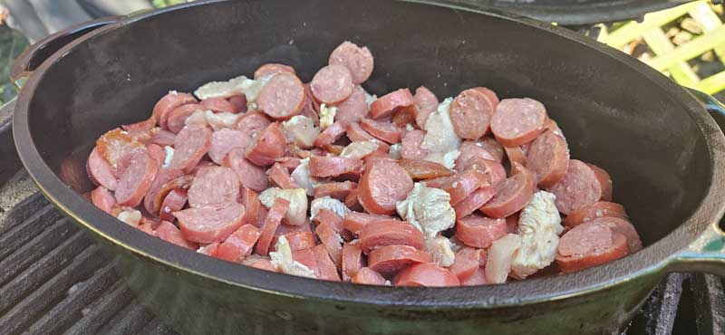 Diced chicken and kielbasa in a Dutch oven.