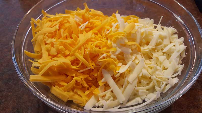 Shredded cheddar and Monterrey jack cheeses in a bowl.