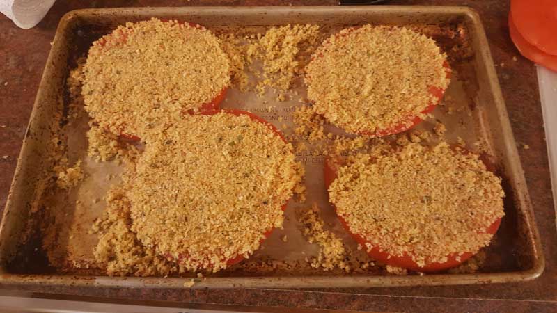 Tomato slices with uncooked breadcrumbs on top.