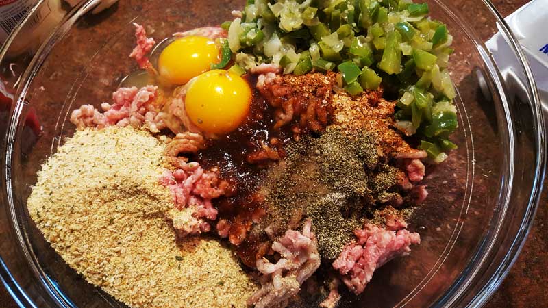Meat, peppers and onions, breadcrumbs, and barbecue sauce in a bowl.