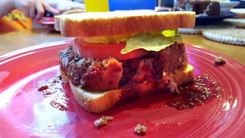 Meatloaf sandwich with tomato and lettuce.