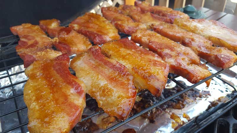 Bacon covered in brown sugar rub on a rack.