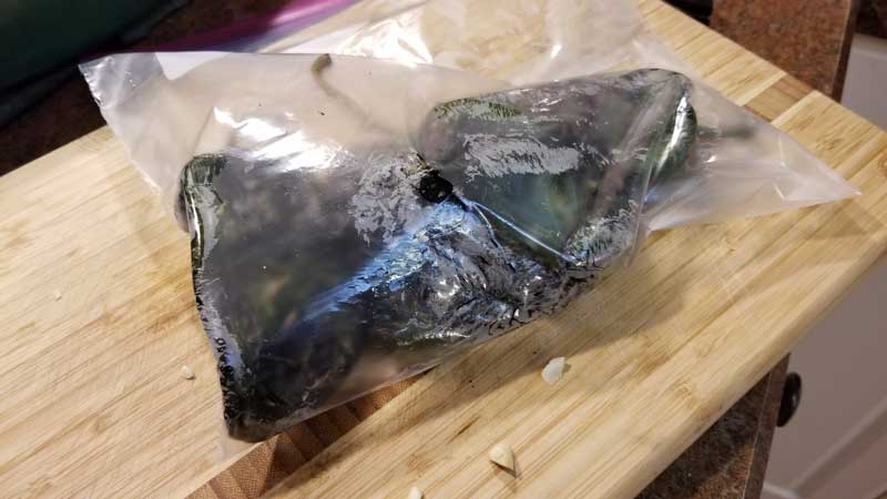 Charred poblano peppers in a Ziploc bag.