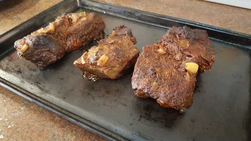 Cooked chuck roast on a metal sheet.