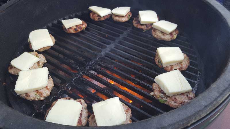 Sausage patties covered with a slice of cheese on the Big Green Egg.