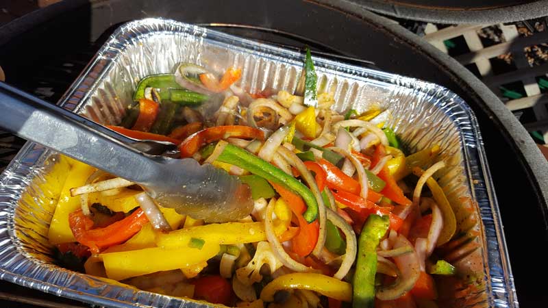 Peppers and onion in an aluminum pan on the Big Green Egg.