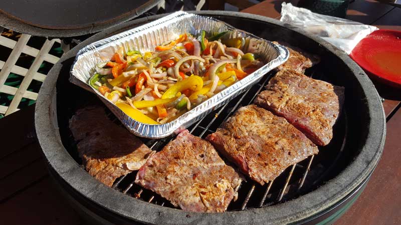 Steaks with peppers and onion mixture on the Big Green Egg.
