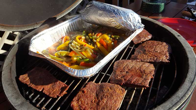 Steaks, peppers and onion mixture, and wrapped tortillas on the Big Green Egg.