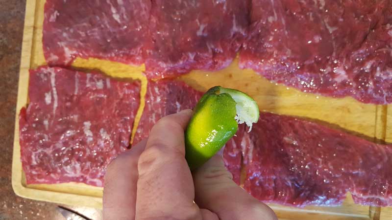 Lime juice being squeezed from a lime onto the skirt steak.