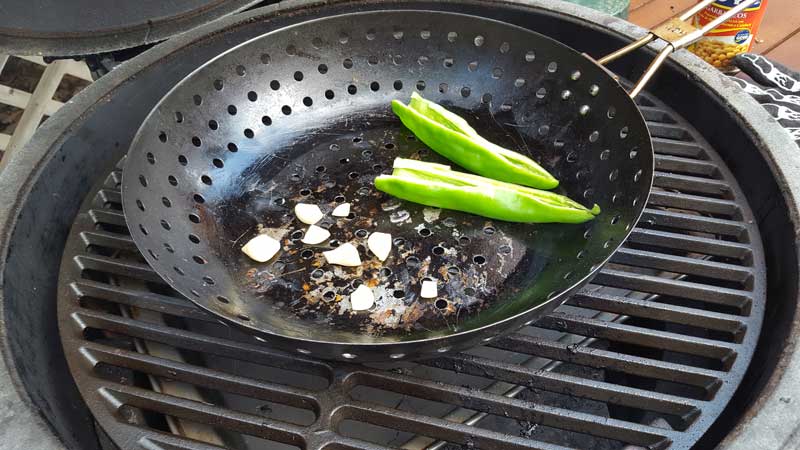 Garlic and chiles in a wok on the Big Green Egg.