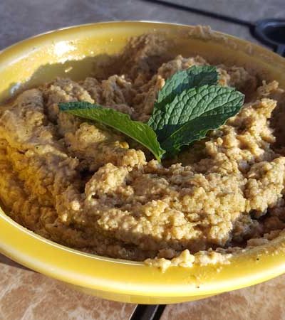 Hummus in a bowl with a mint garnish.