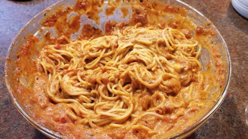 Spaghetti, sauce, and ricotta cheese mixed in a bowl.