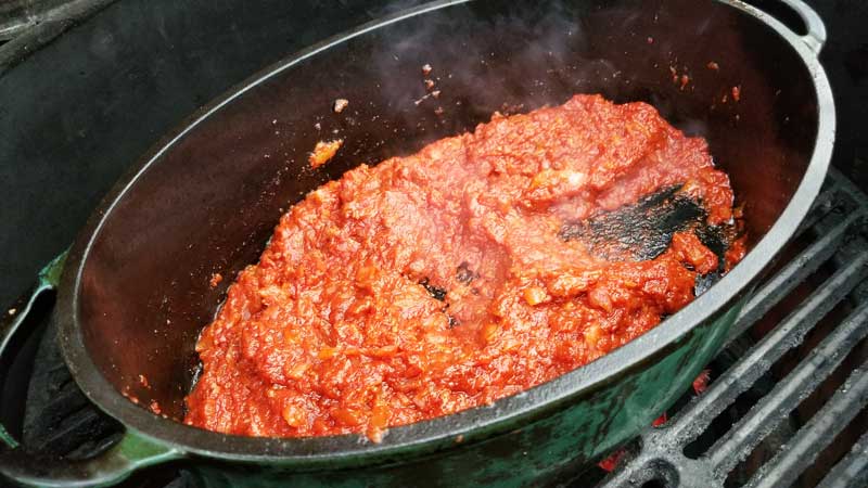 Tomato paste and onions cooking in the Dutch oven.
