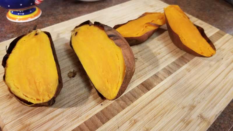 Halved sweet potatoes on a cutting board.