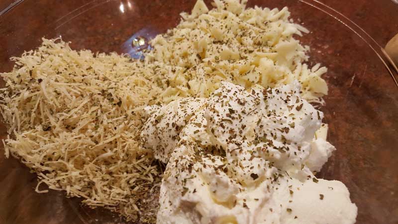 Parmesan, mozzarella, and ricotta cheese covered in salt, pepper, oregano, and basil in a bowl.