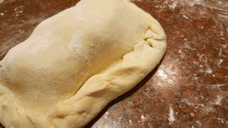 Dough folded over cheese mixture with the ends crimped.