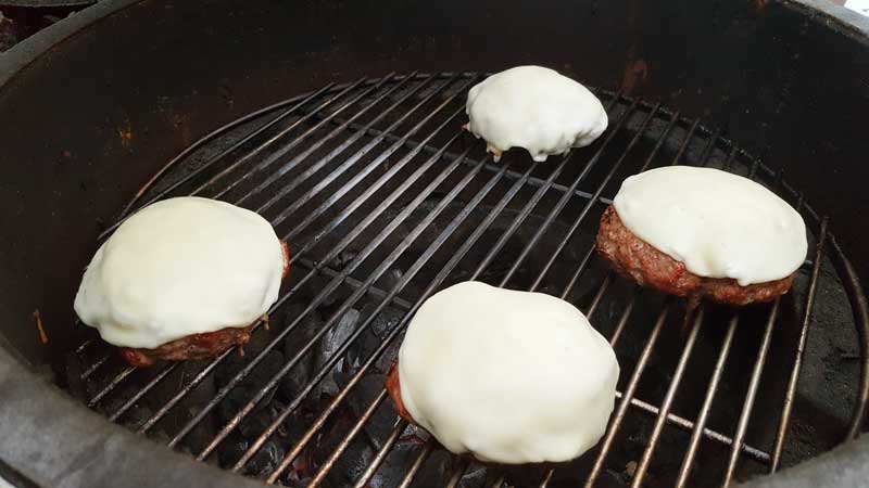 Burger topped with cheese on the Big Green Egg.