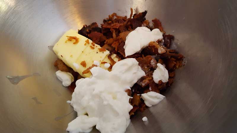Butter, bacon, and sour cream in a metal bowl.