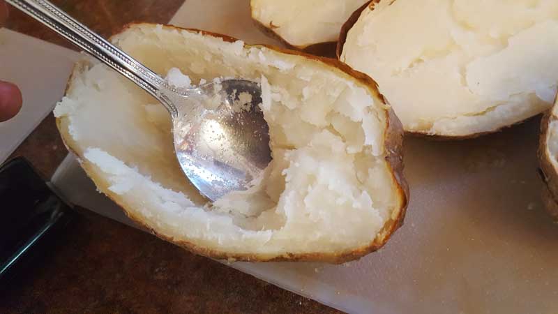 Sliced potato with insides being scooped out.